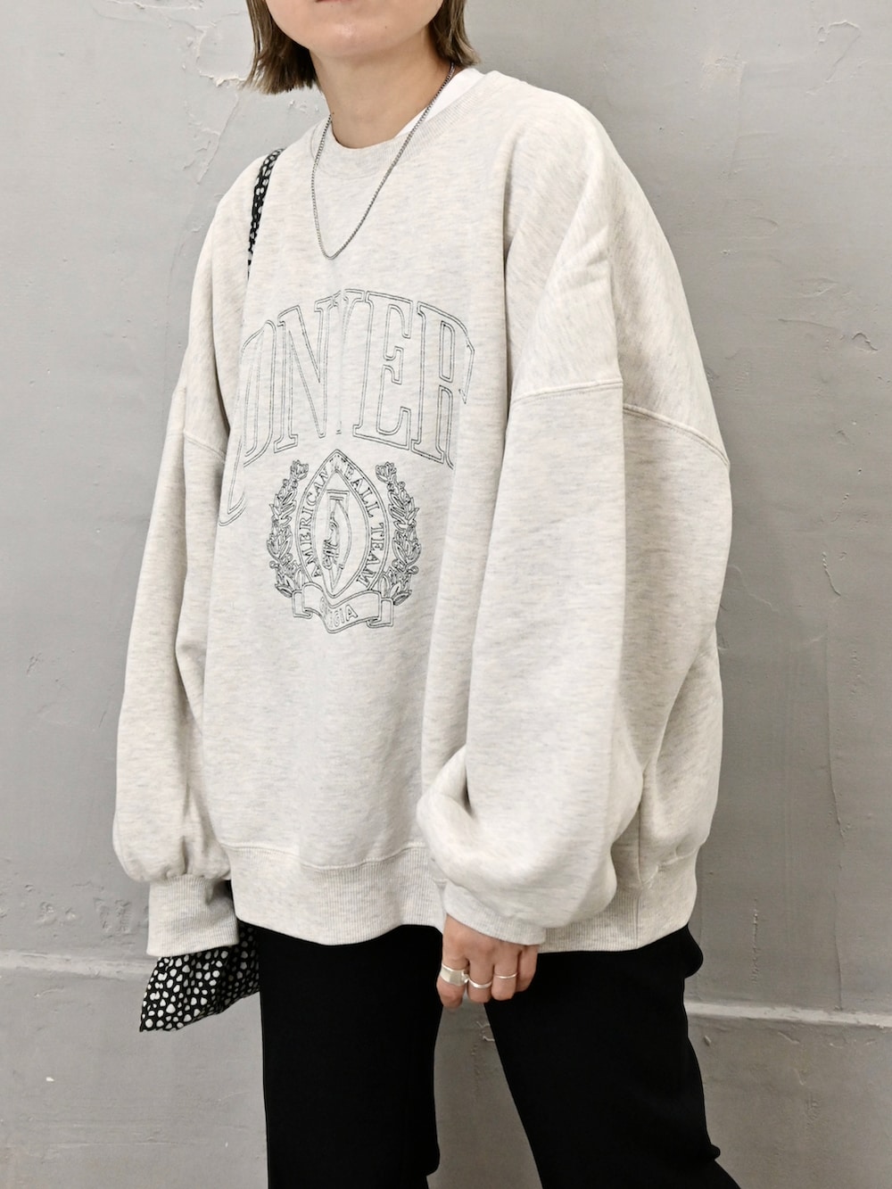 ブラック系のブルゾン、ホワイト系のスウェット、ブラック系のスラックスを着用したレディースの秋コーディネートの3枚目の写真