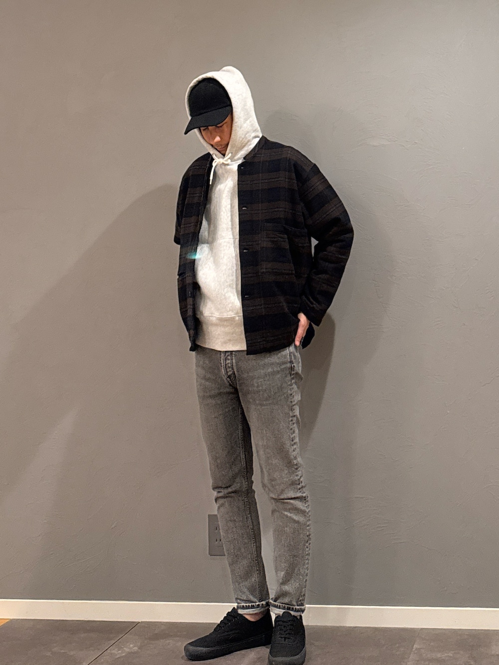 グレー系のパーカー、グレー系のデニムパンツ、ブラック系のスニーカーを着用したメンズの秋コーディネートの4枚目の写真