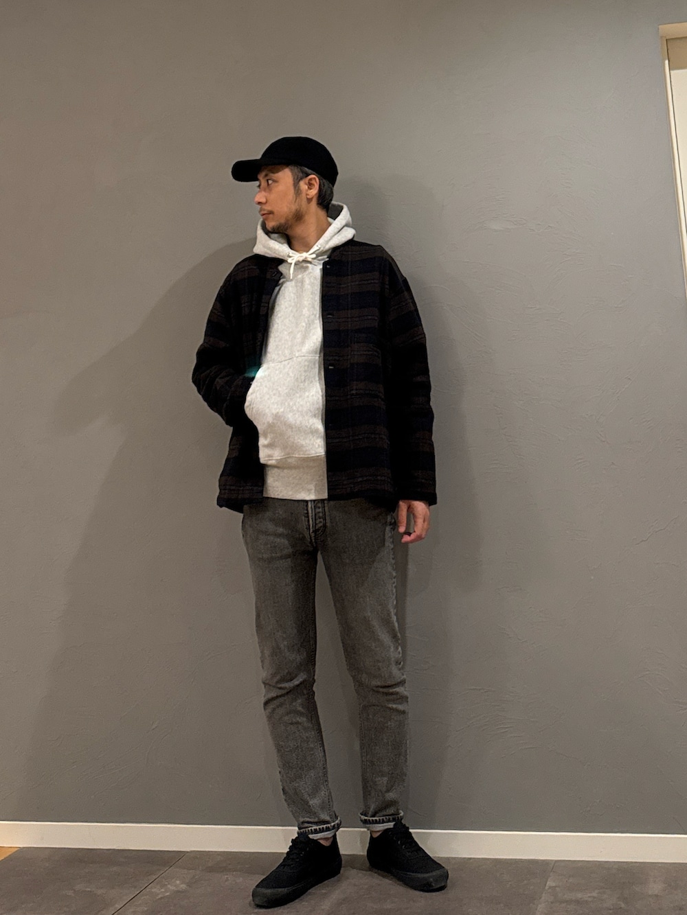 グレー系のパーカー、グレー系のデニムパンツ、ブラック系のスニーカーを着用したメンズの秋コーディネートの2枚目の写真