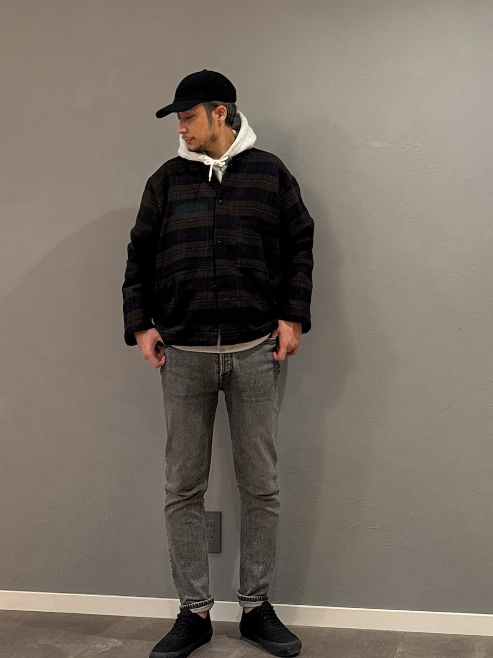 グレー系のパーカー、グレー系のデニムパンツ、ブラック系のスニーカーを着用したメンズの秋コーディネートの5枚目の写真