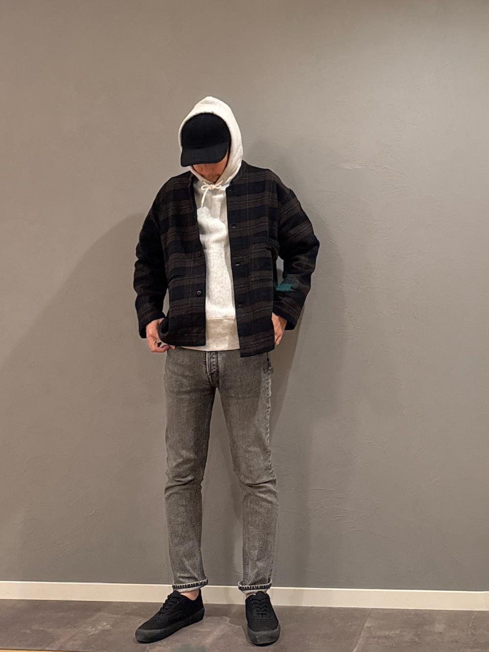 グレー系のパーカー、グレー系のデニムパンツ、ブラック系のスニーカーを着用したメンズの秋コーディネートの3枚目の写真