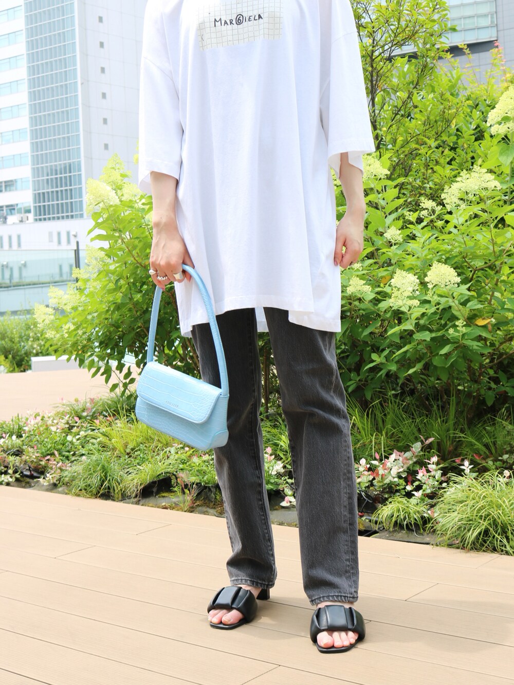 ブラック系のデニムパンツ、ブルー系のハンドバッグ、ピンク系のサンダルを着用したレディースの夏コーディネートの3枚目の写真