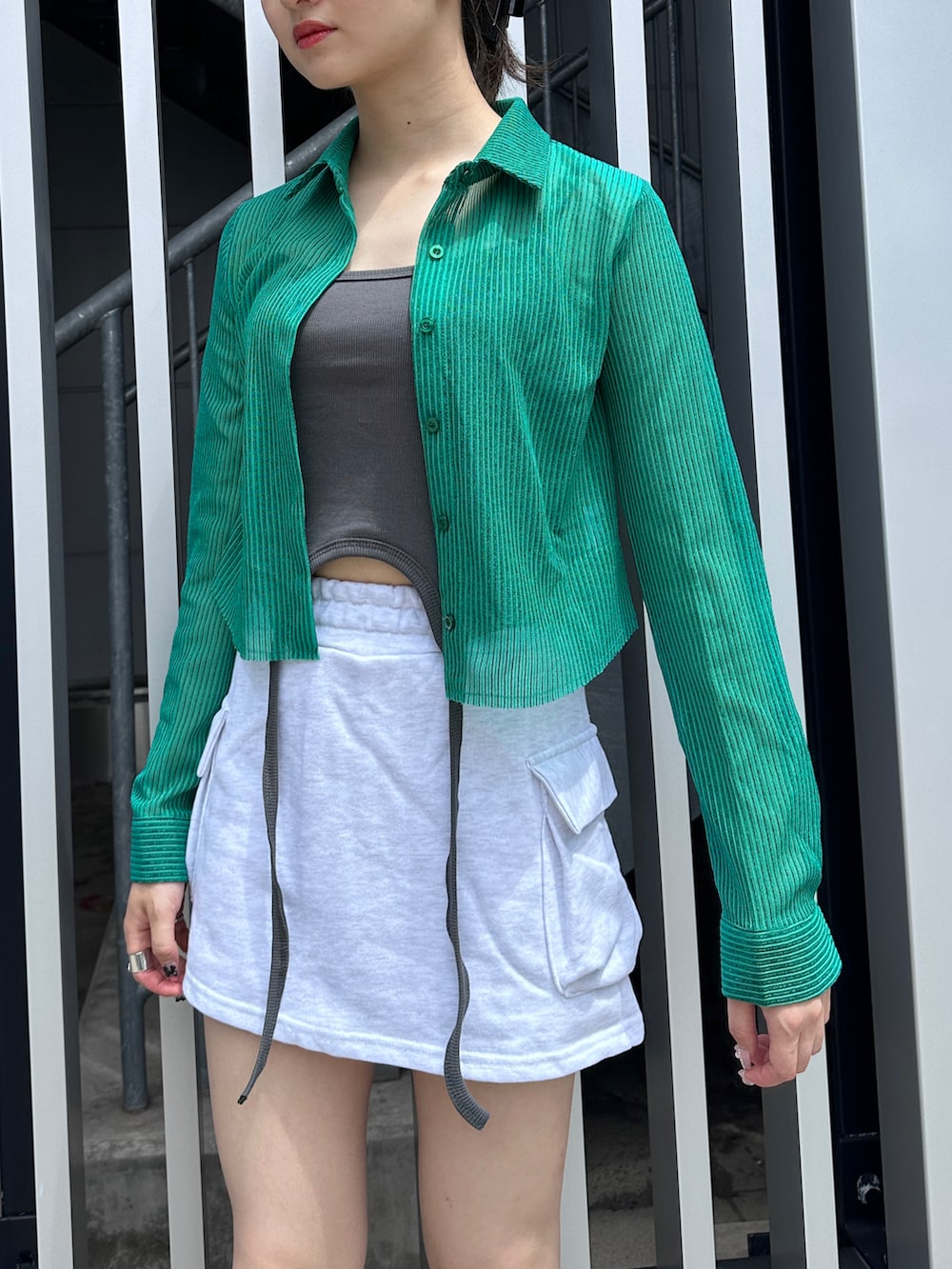 グリーン系のシャツ/ブラウス、グレー系のスカート、ブラック系のブーツを着用したレディースの夏コーディネートの2枚目の写真