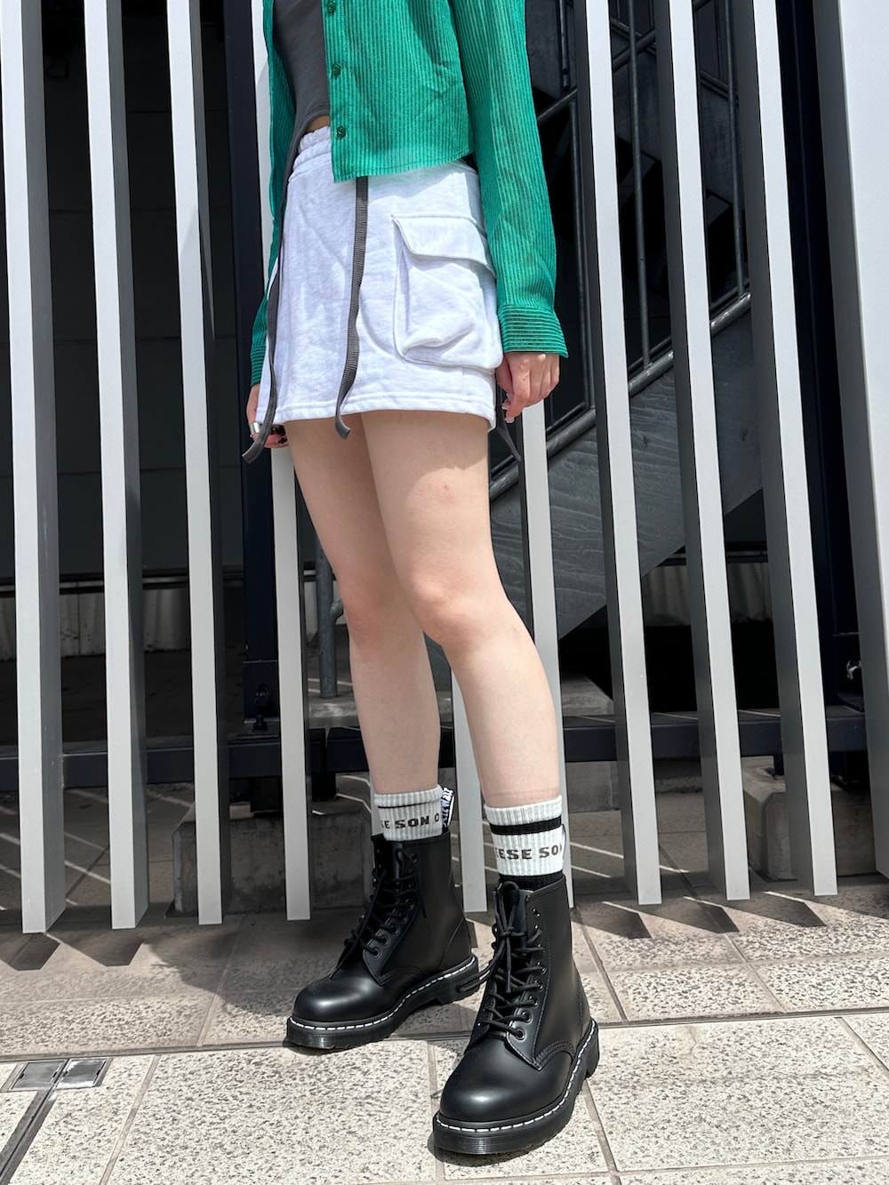 グリーン系のシャツ/ブラウス、グレー系のスカート、ブラック系のブーツを着用したレディースの夏コーディネートの3枚目の写真