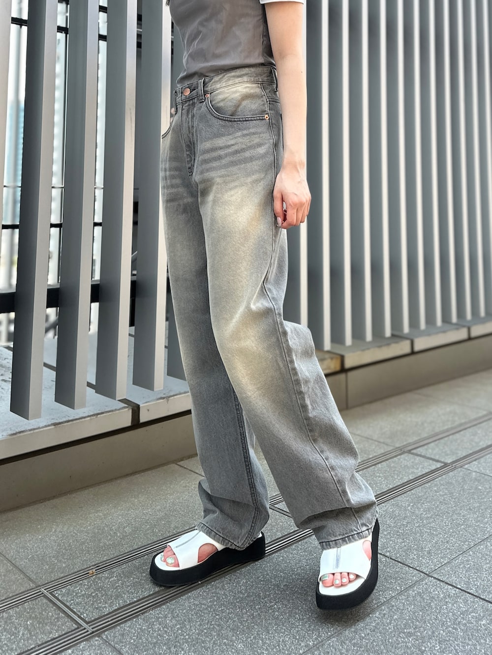 グレー系のデニムパンツ、ホワイト系のサンダル、グレー系のTシャツ/カットソーを着用したレディースの夏コーディネートの4枚目の写真