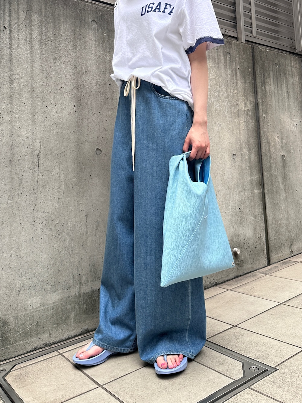 ホワイト系のTシャツ/カットソー、ブルー系のデニムパンツ、ブルー系のハンドバッグを着用したレディースの夏コーディネートの3枚目の写真