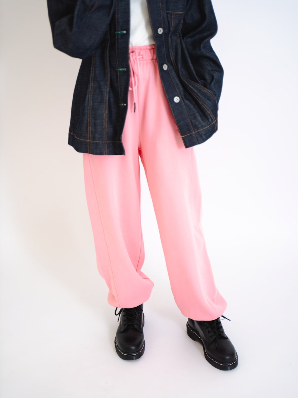 ピンク系のスウェットパンツ、ホワイト系のタンクトップ、ブラック系のデニムジャケットを着用したレディースの夏コーディネートの3枚目の写真