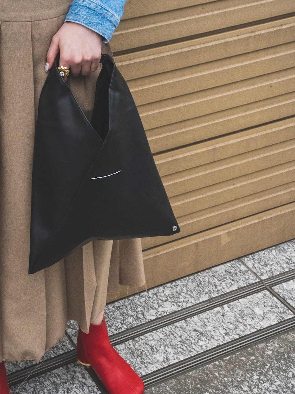 ベージュ系のスカート、ブルー系のデニムジャケット、ブラック系のハンドバッグを着用したレディースの春コーディネートの3枚目の写真