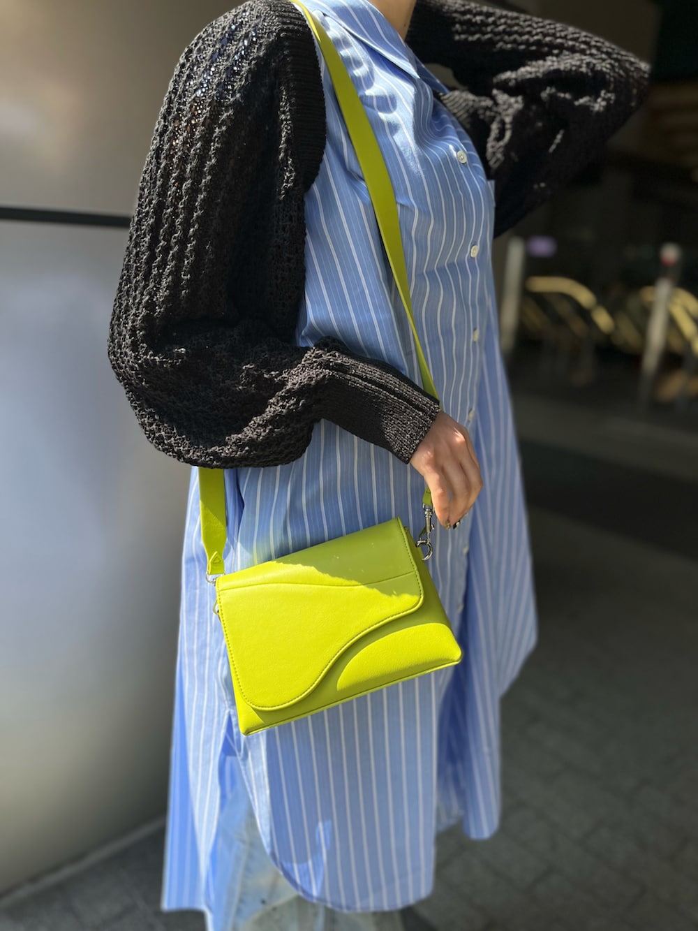 ブルー系のシャツワンピース、ブラック系のカーディガン/ボレロ、グリーン系のショルダーバッグを着用したレディースの春コーディネートの4枚目の写真