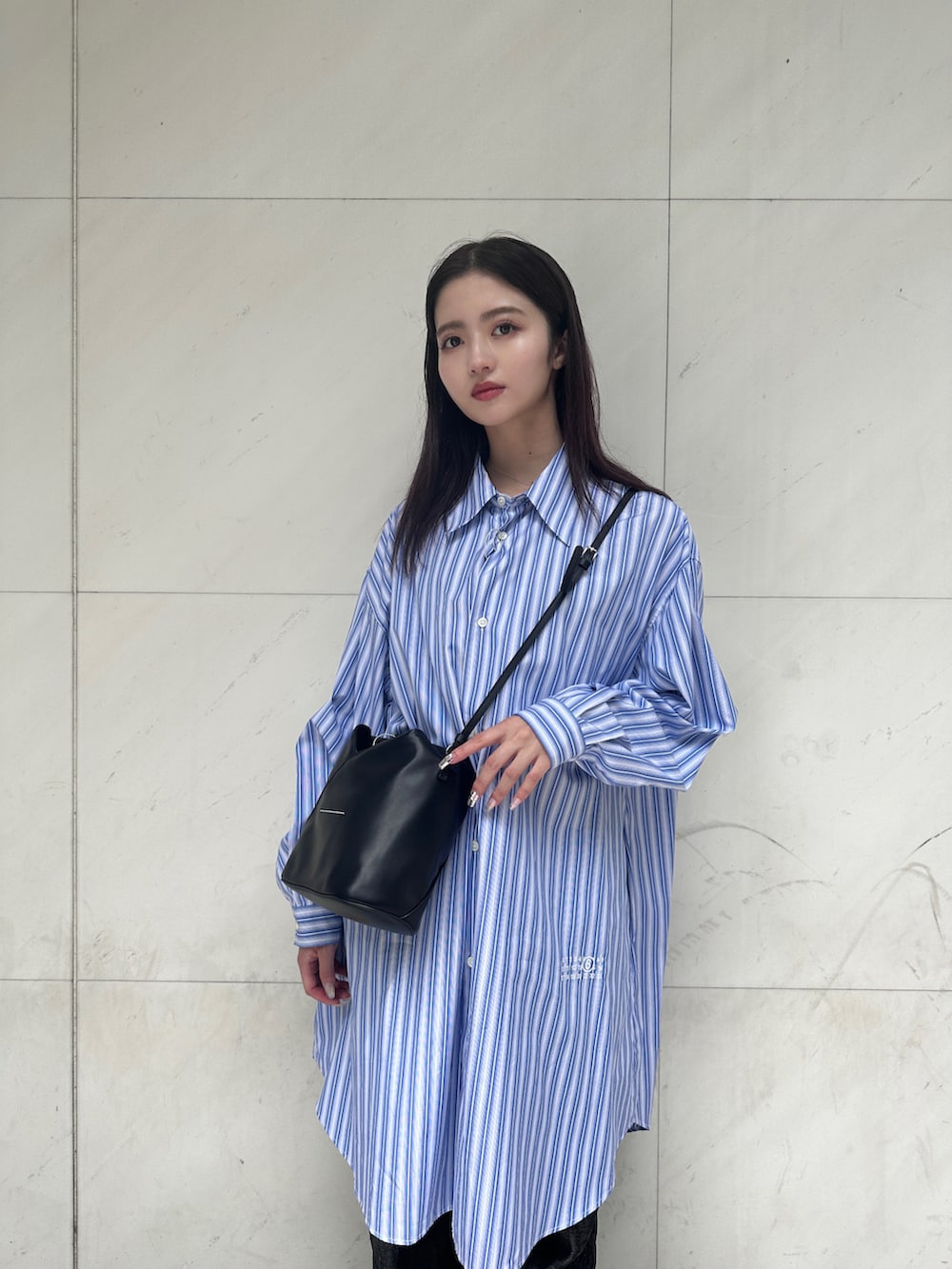 ブラック系のショルダーバッグ、ブルー系のシャツワンピース、ブルー系のデニムパンツを着用したレディースの夏コーディネートの2枚目の写真