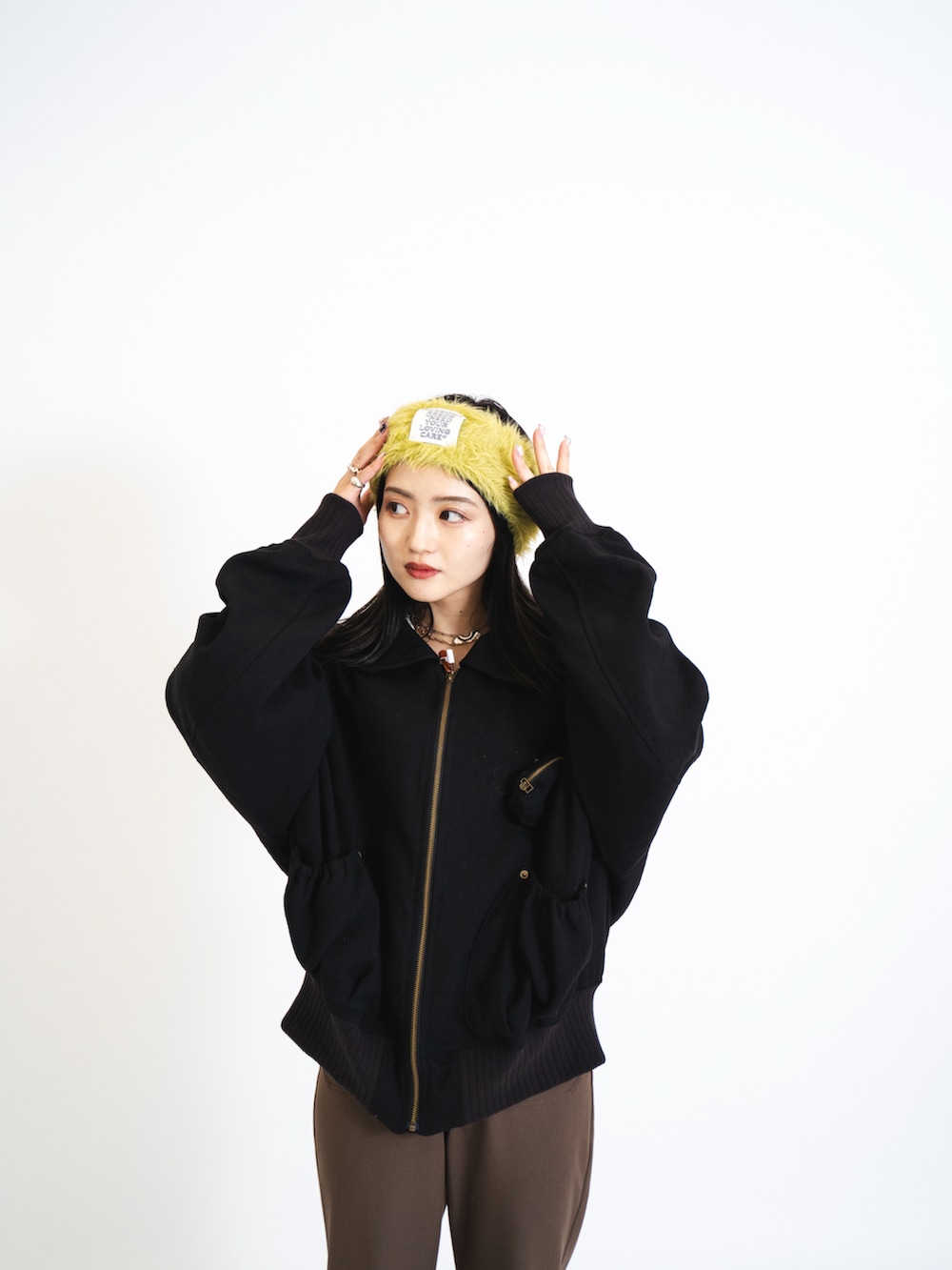 ブラック系のブルゾン、ブラウン系のスラックス、ブラック系のブーツを着用したレディースの夏コーディネートの2枚目の写真