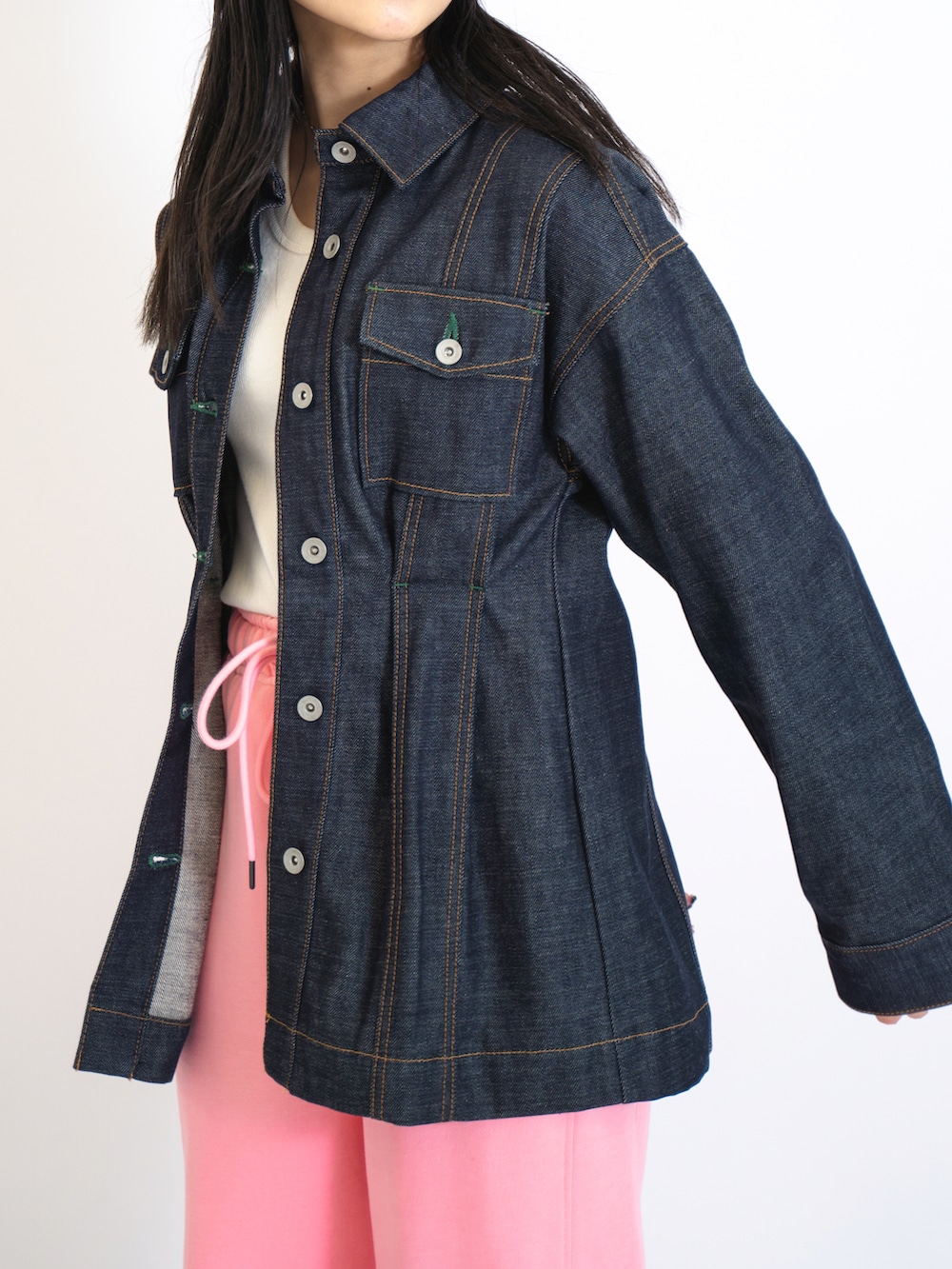 ピンク系のスウェットパンツ、ホワイト系のタンクトップ、ブラック系のデニムジャケットを着用したレディースの夏コーディネートの2枚目の写真