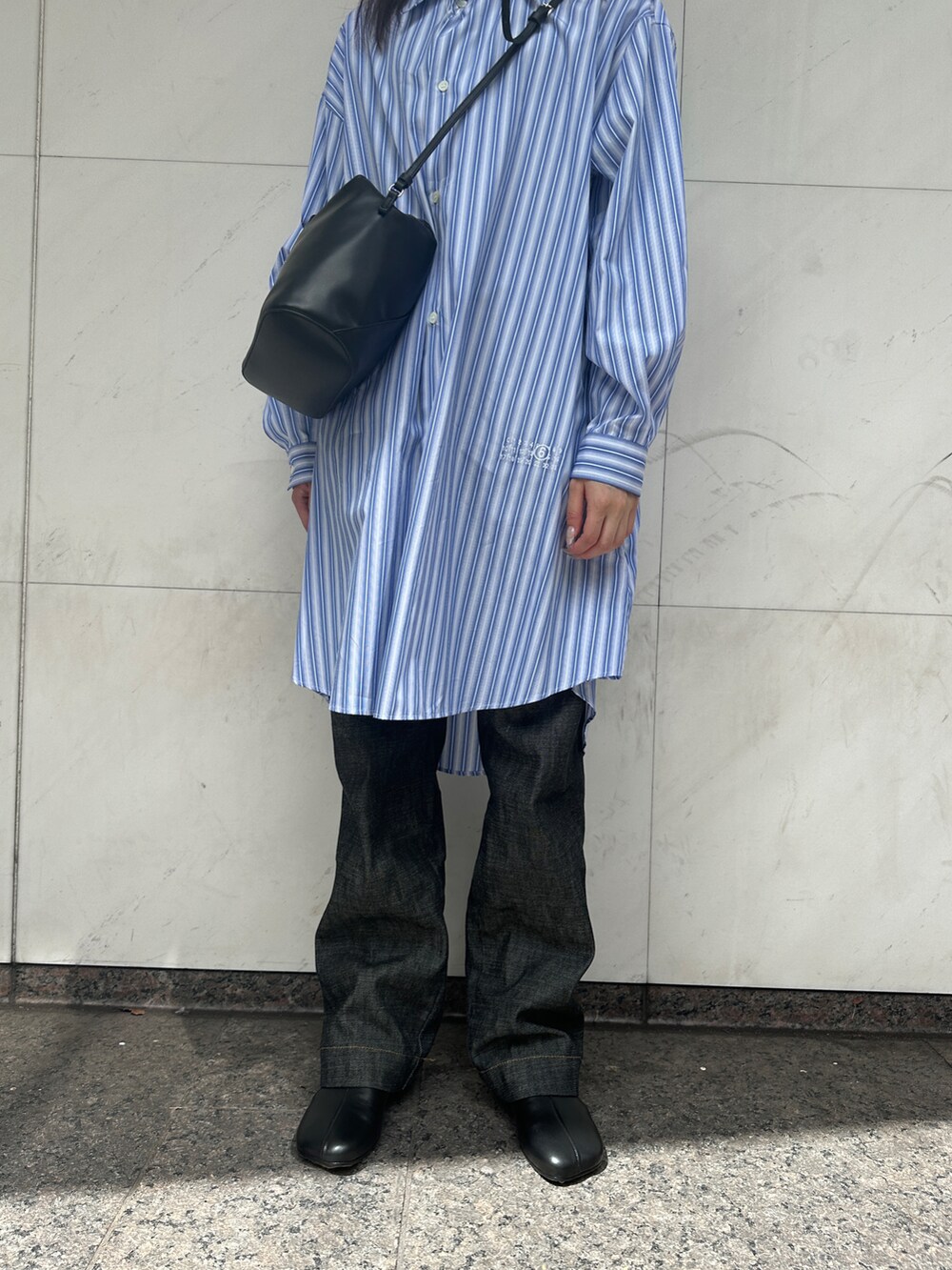 ブラック系のショルダーバッグ、ブルー系のシャツワンピース、ブルー系のデニムパンツを着用したレディースの夏コーディネートの3枚目の写真