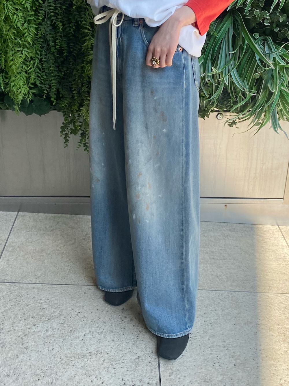 ブラック系のブーツ、ブルー系のデニムパンツを着用したレディースの春コーディネートの2枚目の写真