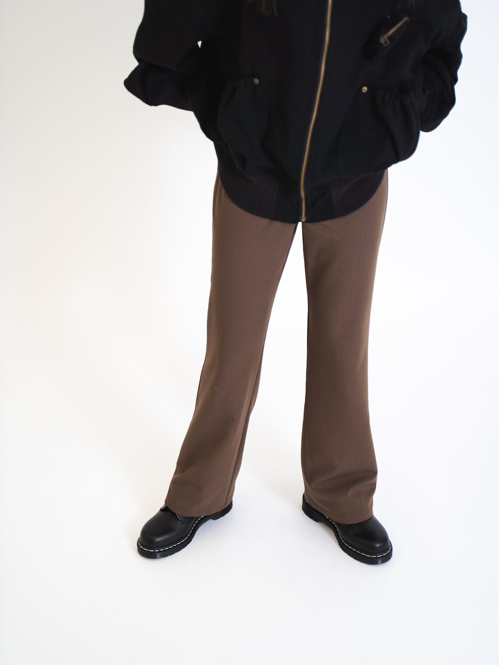 ブラック系のブルゾン、ブラウン系のスラックス、ブラック系のブーツを着用したレディースの夏コーディネートの3枚目の写真