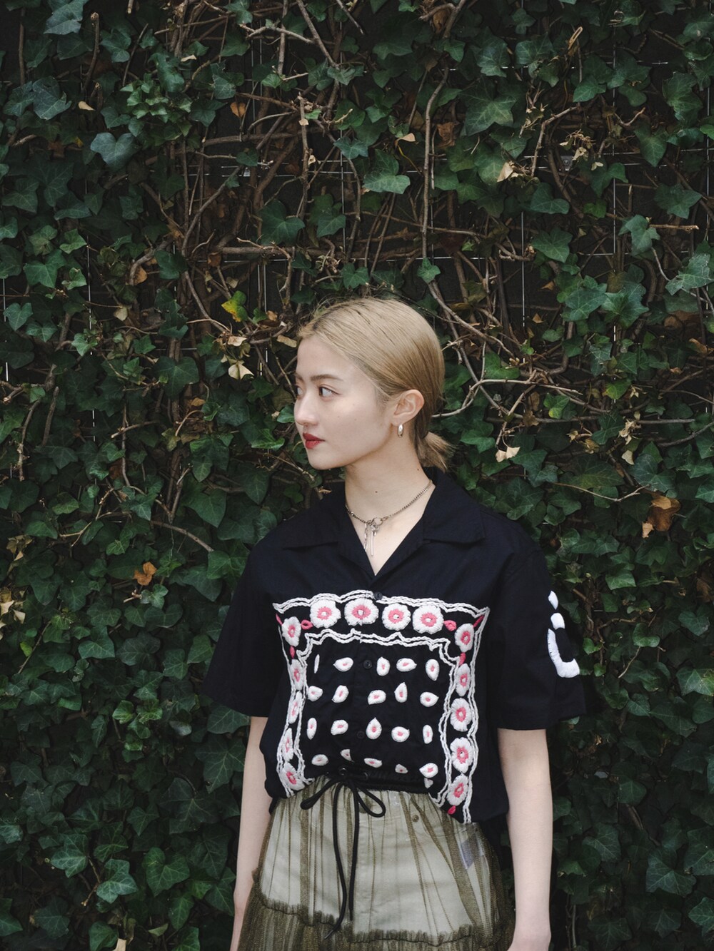 ゴールド系のスカート、ホワイト系のサンダル、ブラック系のシャツ/ブラウスを着用したレディースの春コーディネートの2枚目の写真