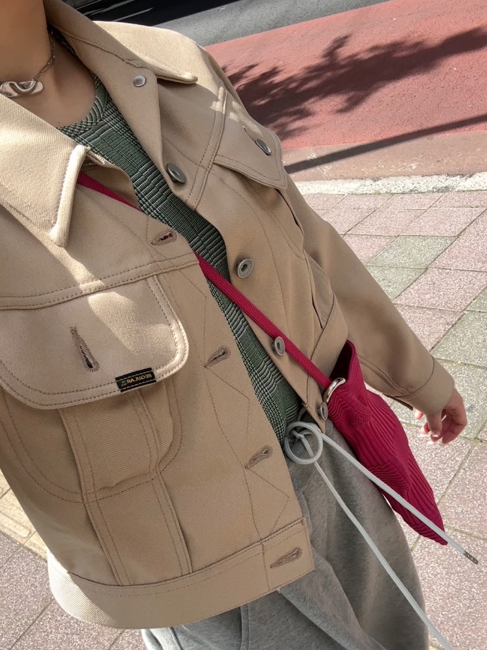 ベージュ系のその他アウター、グリーン系のキャミソール、グレー系のスウェットパンツを着用したレディースの春コーディネートの2枚目の写真