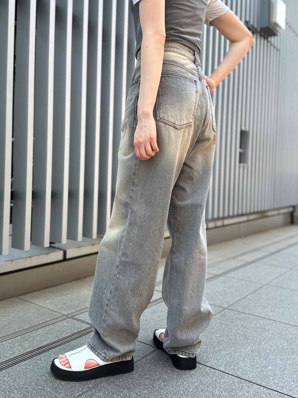 グレー系のデニムパンツ、ホワイト系のサンダル、グレー系のTシャツ/カットソーを着用したレディースの夏コーディネートの5枚目の写真