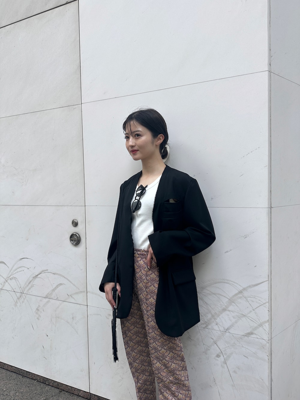 ブラウン系のパンツ、ホワイト系のタンクトップ、ブラック系のジャケット/アウターを着用したレディースの春コーディネートの2枚目の写真