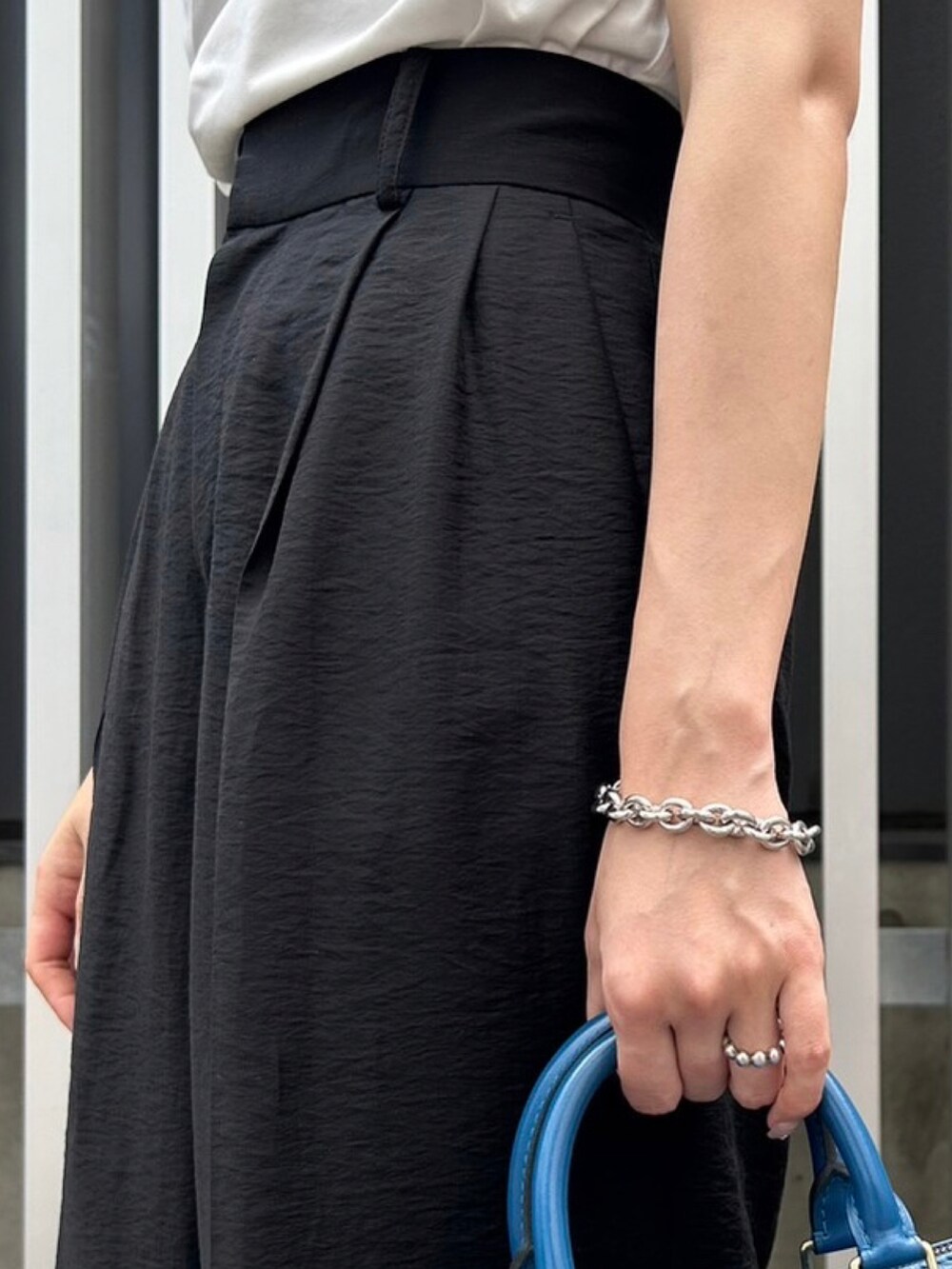 ブラック系のスラックス、ホワイト系のTシャツ/カットソー、ブラック系のサンダルを着用したレディースの夏コーディネートの4枚目の写真