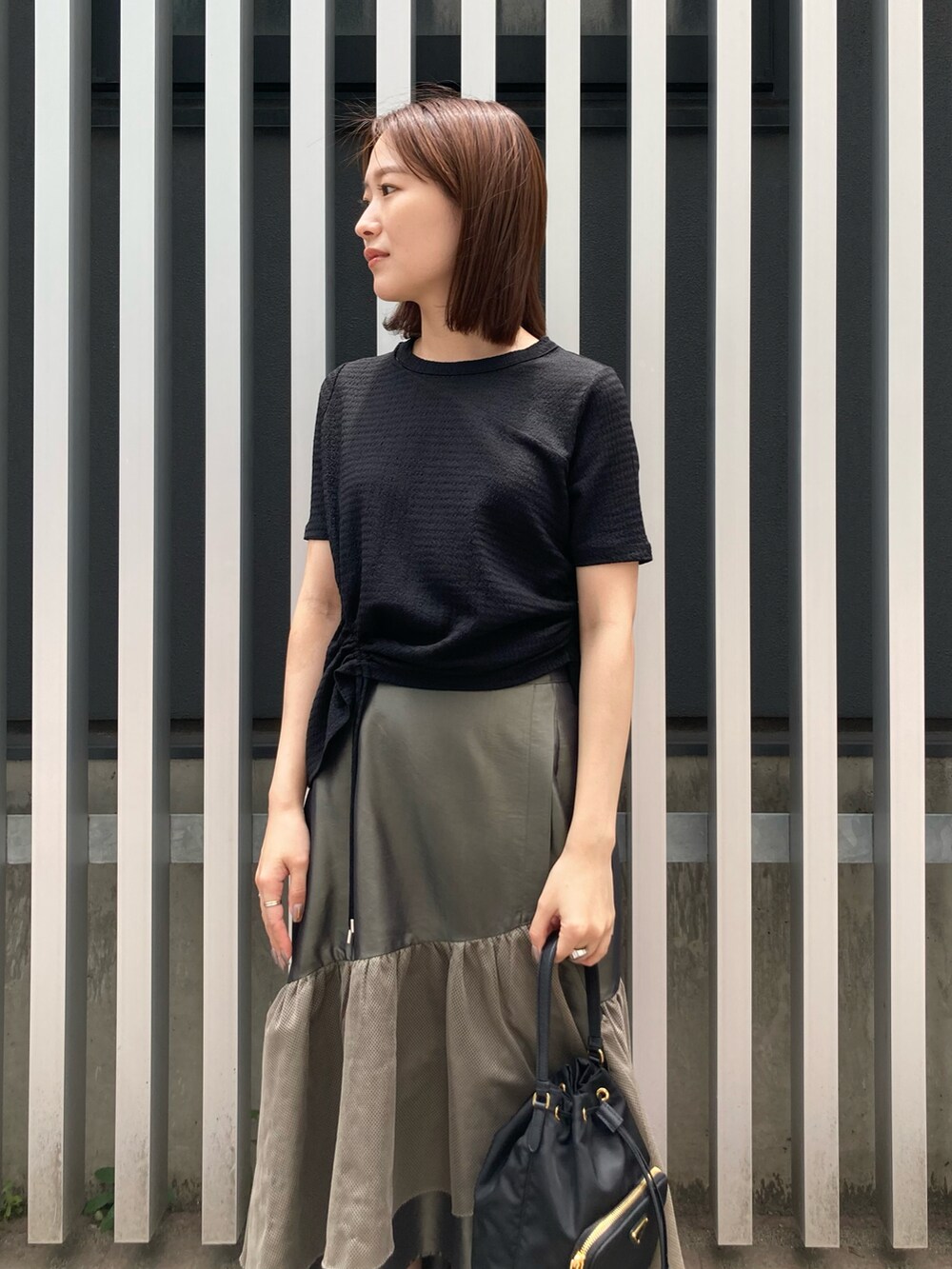 ブラック系のサンダル、グリーン系のスカート、ブラック系のTシャツ/カットソーを着用したレディースの夏コーディネートの2枚目の写真