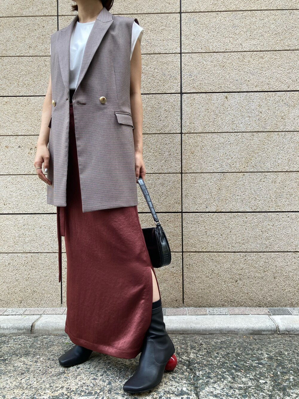 ブラック系のブーツ、ベージュ系のベスト、ホワイト系のTシャツ/カットソーを着用したレディースの秋コーディネートの4枚目の写真