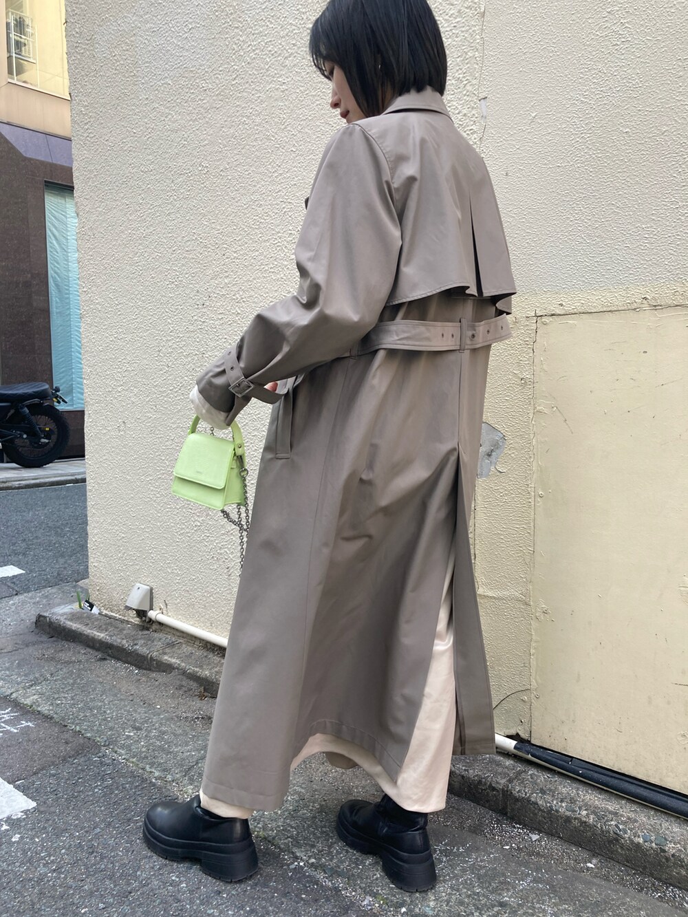 ブラウン系のトレンチコート、グリーン系のワンピース/ドレスを着用したレディースの冬コーディネートの2枚目の写真