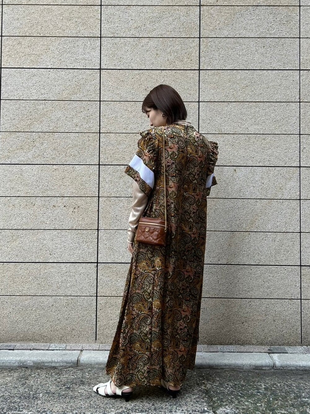 ブラウン系のワンピース/ドレス、ベージュ系のTシャツ/カットソー、ホワイト系のサンダルを着用したレディースの春コーディネートの2枚目の写真