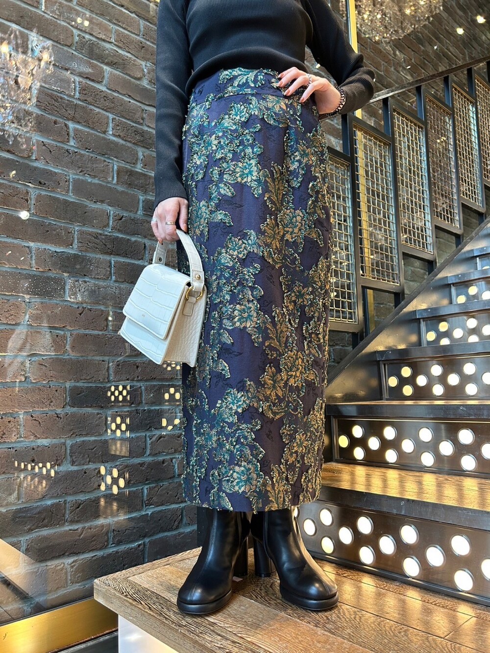 ホワイト系のブルゾン、ブルー系のスカート、ブラック系のニット/セーターを着用したレディースの秋コーディネートの5枚目の写真