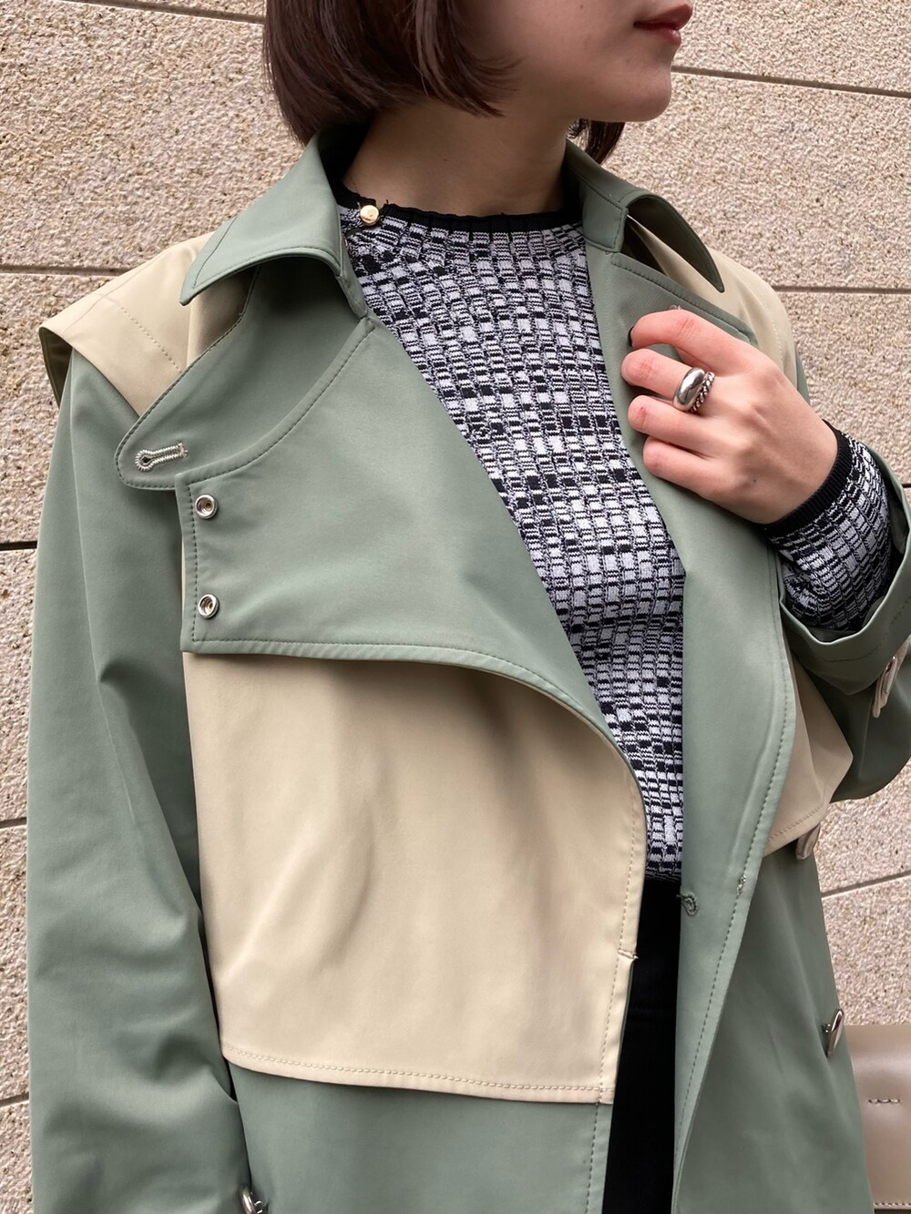 ベージュ系のハンドバッグ、グリーン系のトレンチコート、ブラック系のブーツを着用したレディースの冬コーディネートの4枚目の写真