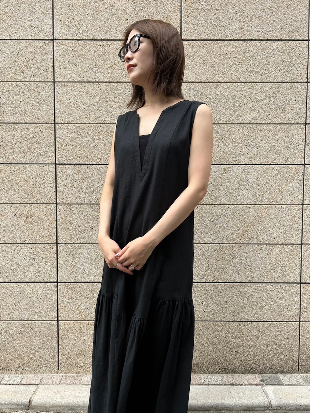 パープル系のハンドバッグ、ブラック系のスニーカー、ブラック系のワンピースを着用したレディースの夏コーディネートの4枚目の写真