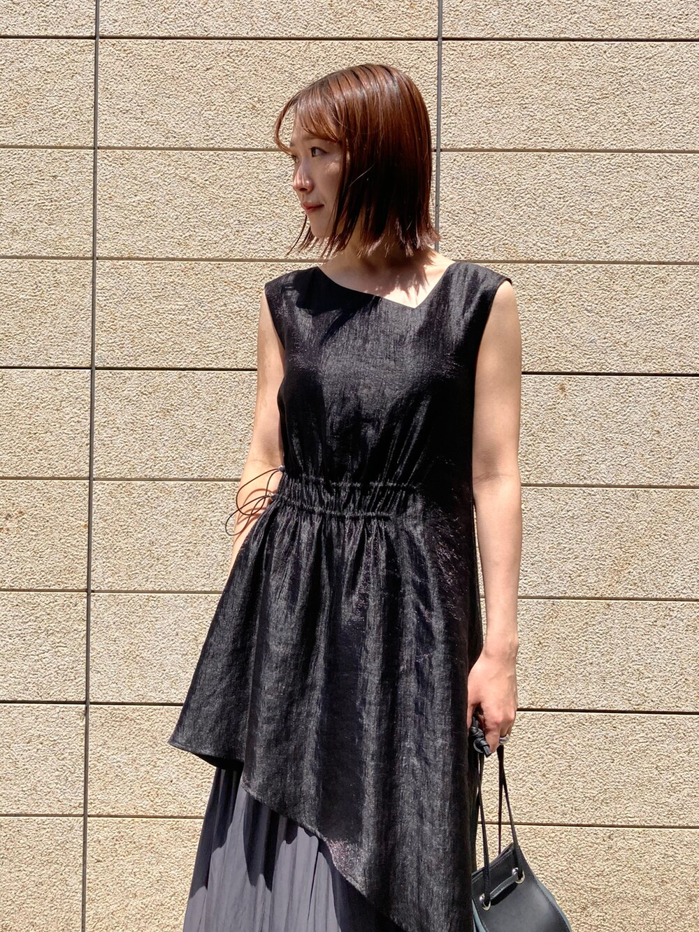 ブラック系のワンピース、ブラック系のバッグ、ブラック系のサンダルを着用したレディースの春コーディネートの2枚目の写真