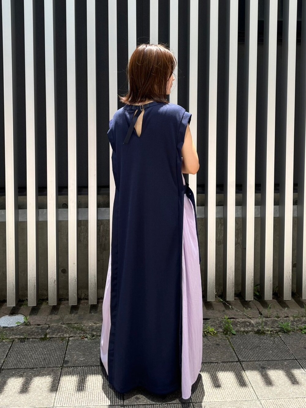 パープル系のハンドバッグ、パープル系のワンピース、ブラック系のシューズを着用したレディースの夏コーディネートの2枚目の写真