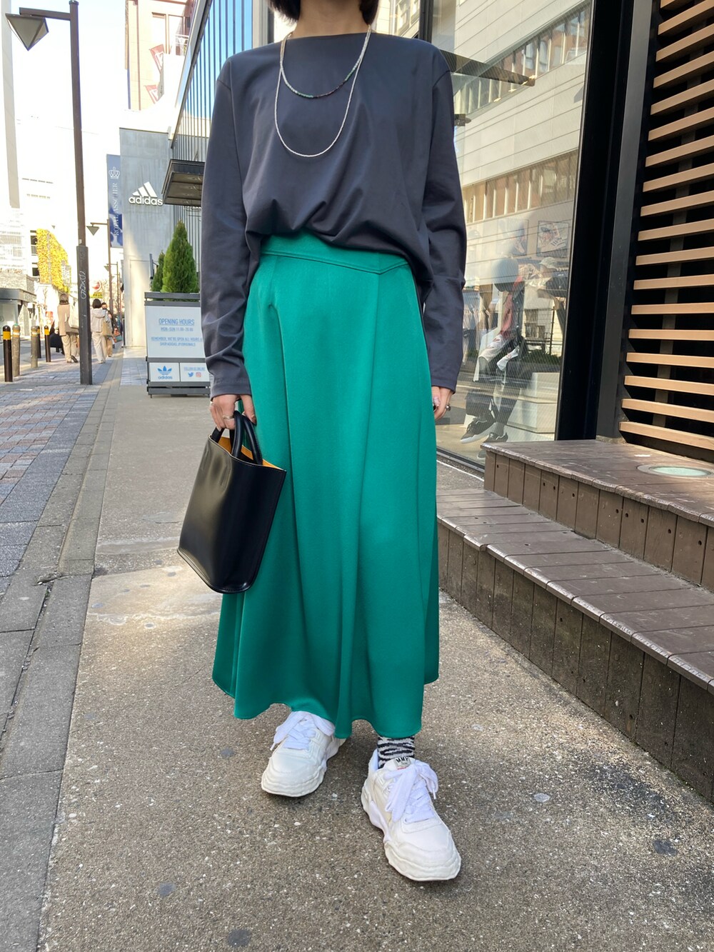 グリーン系のスカート、ブラック系のハンドバッグ、グレー系のその他トップスを着用したレディースの春コーディネートの3枚目の写真