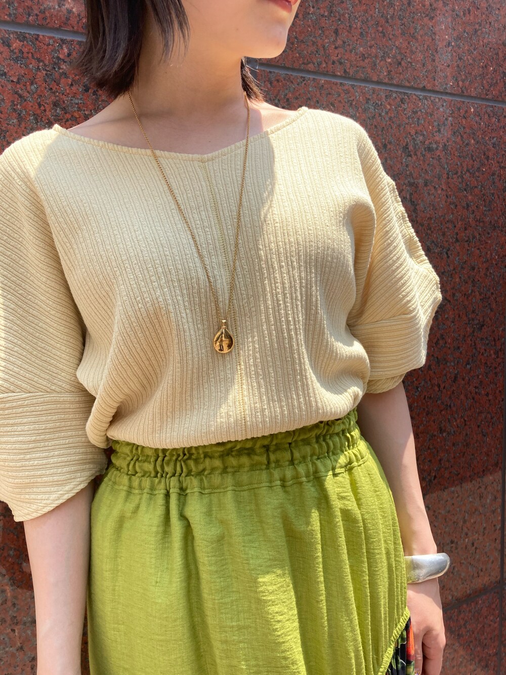 イエロー系のTシャツ/カットソー、オレンジ系のスカート、ブラウン系のサンダルを着用したレディースの春コーディネートの2枚目の写真