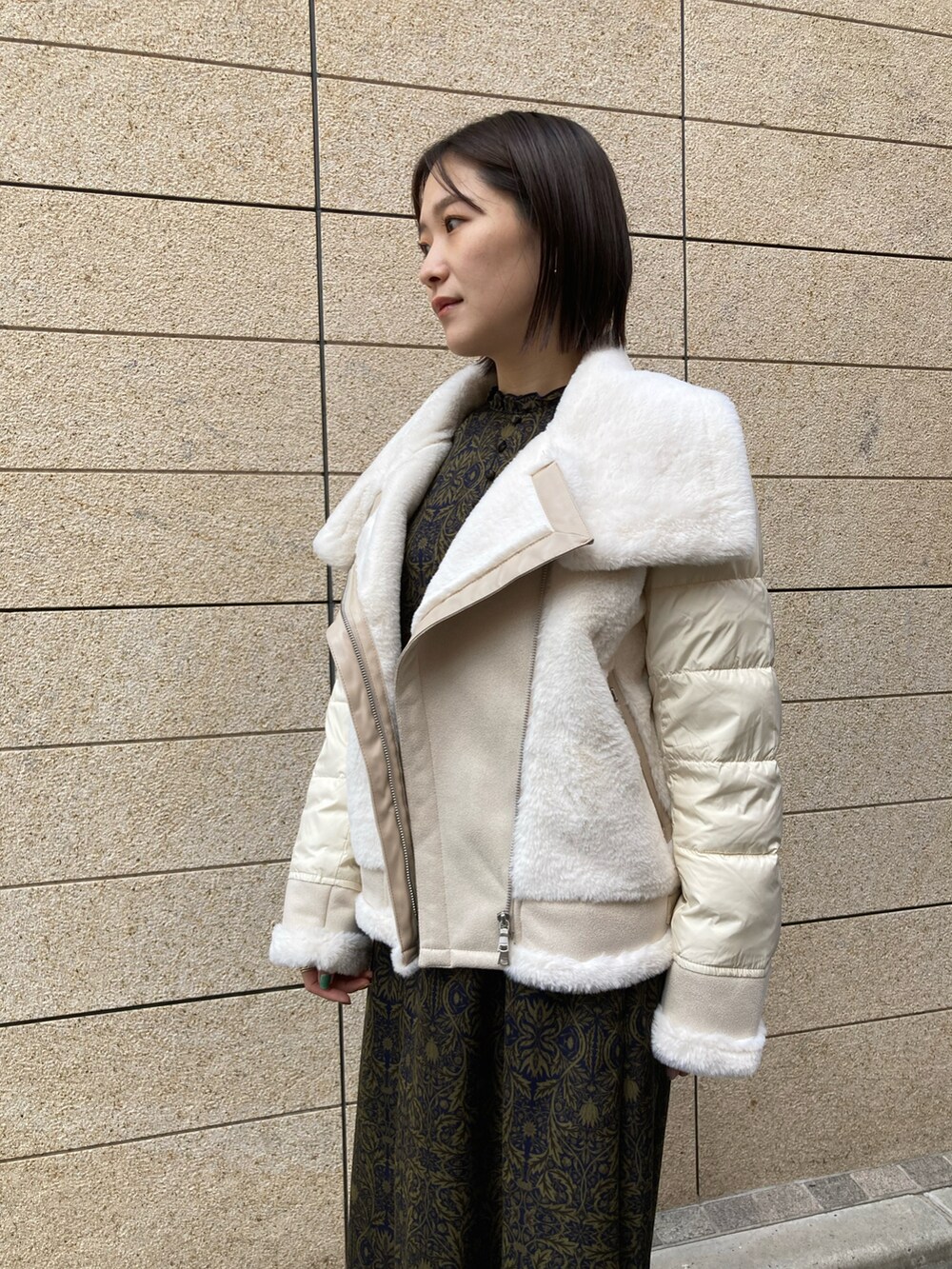 ホワイト系のブルゾン、ブルー系のワンピース、ブラック系のブーツを着用したレディースの秋コーディネートの2枚目の写真