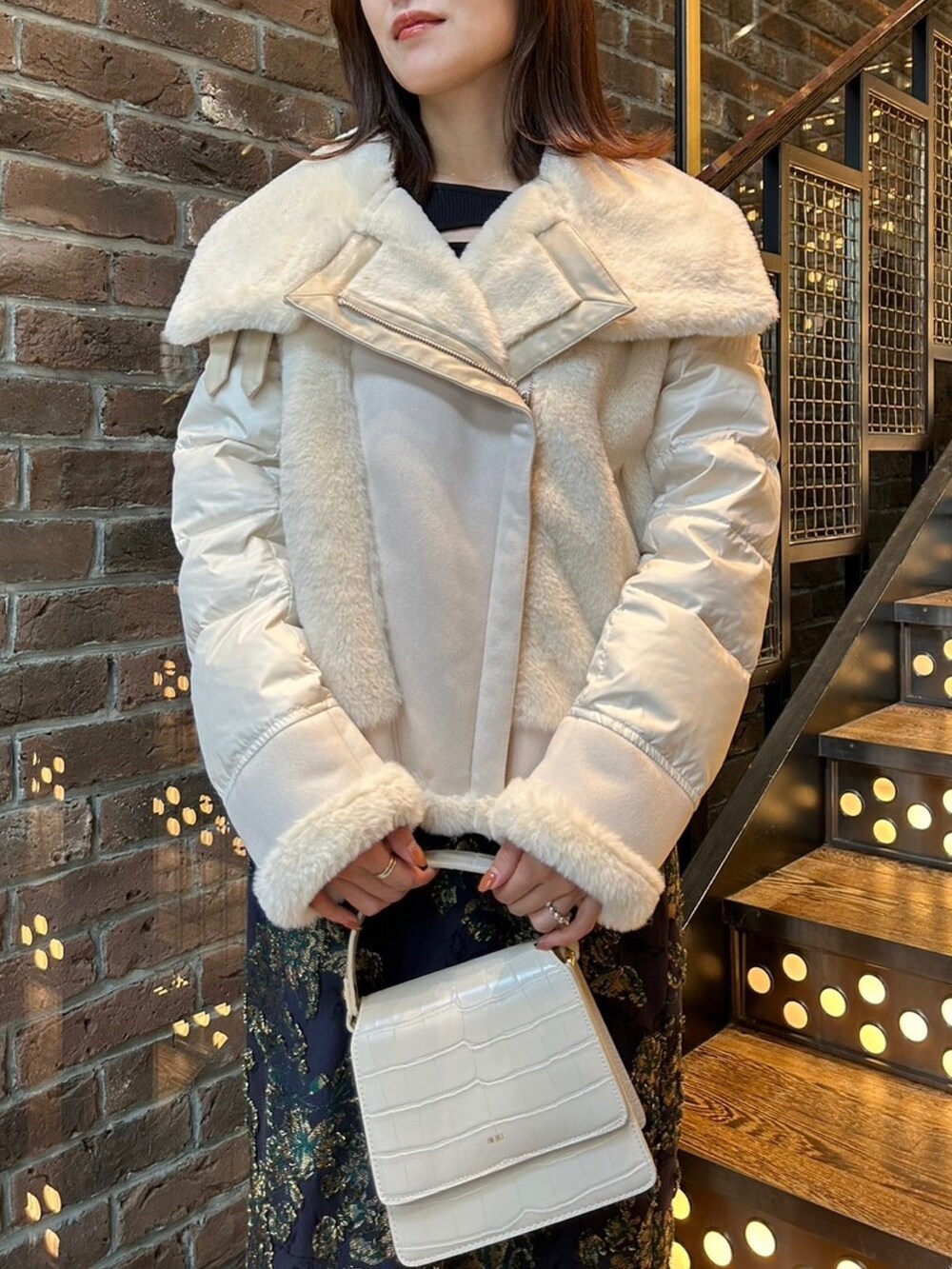 ホワイト系のブルゾン、ブルー系のスカート、ブラック系のニット/セーターを着用したレディースの秋コーディネートの2枚目の写真