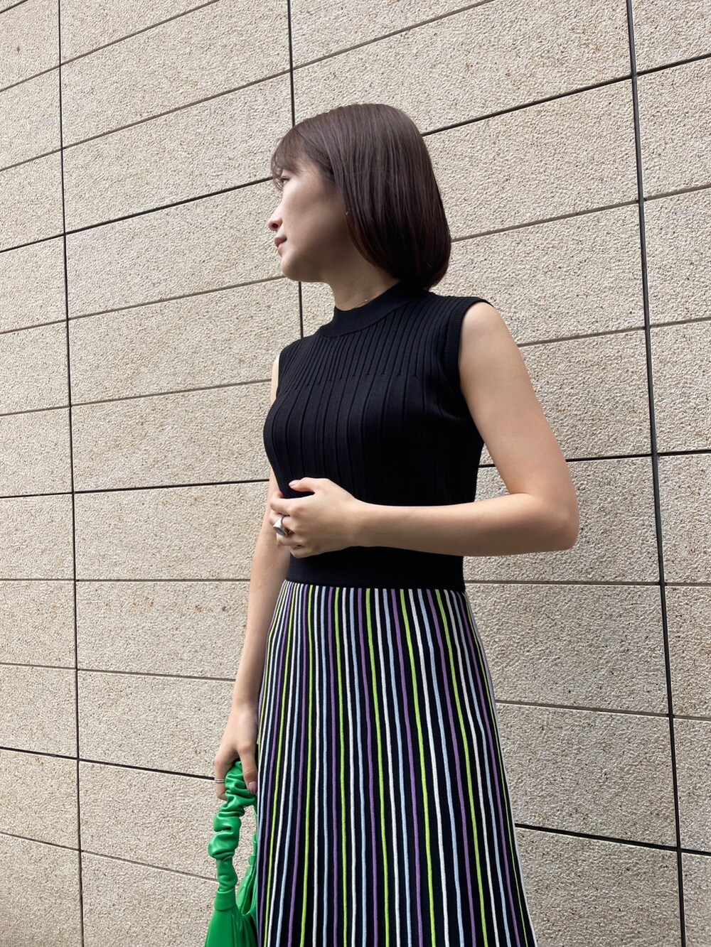 ブラック系のジャケット/アウター、ブラック系のワンピース、グリーン系のハンドバッグを着用したレディースの春コーディネートの3枚目の写真