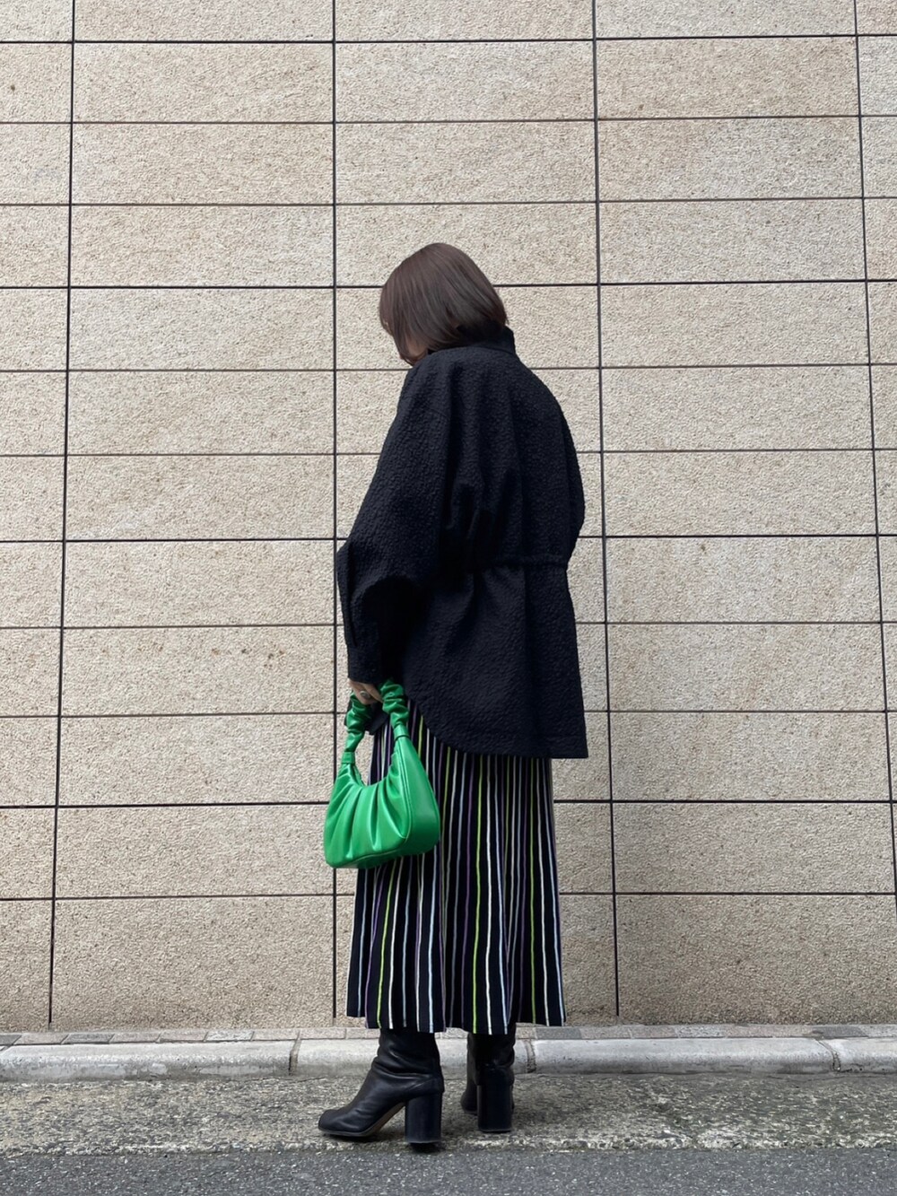 ブラック系のジャケット/アウター、ブラック系のワンピース、グリーン系のハンドバッグを着用したレディースの春コーディネートの2枚目の写真