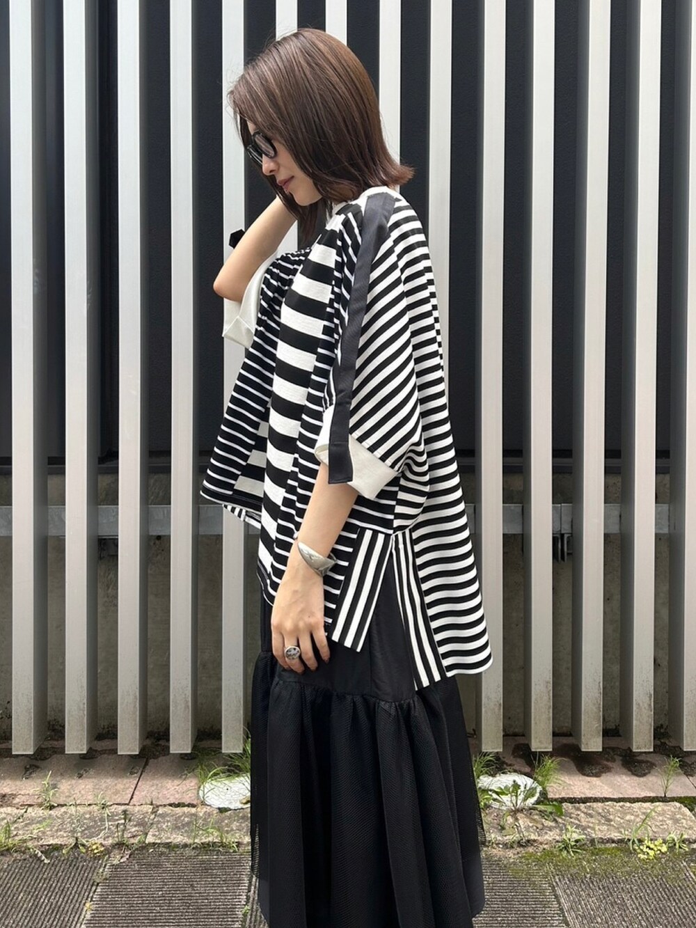 ブラック系のスカート、ブラック系のサンダル、ブラック系のTシャツ/カットソーを着用したレディースの夏コーディネートの3枚目の写真