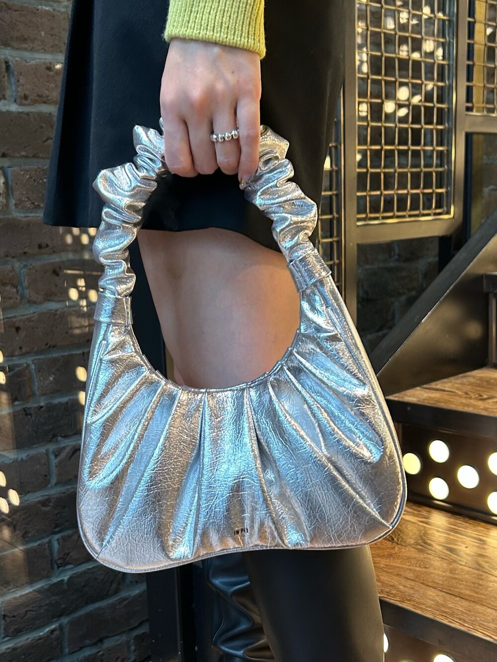 ブラウン系のチェスターコート、イエロー系のニット/セーター、ブラック系のその他パンツを着用したレディースの秋コーディネートの7枚目の写真