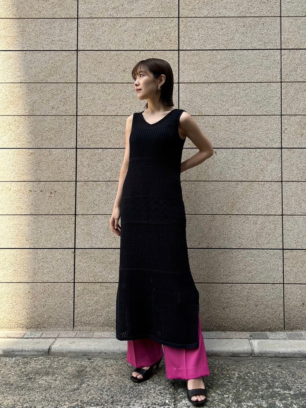 ピンク系のパンツ、ブラック系のニット/セーター、ブラック系のワンピースを着用したレディースの春コーディネートの3枚目の写真