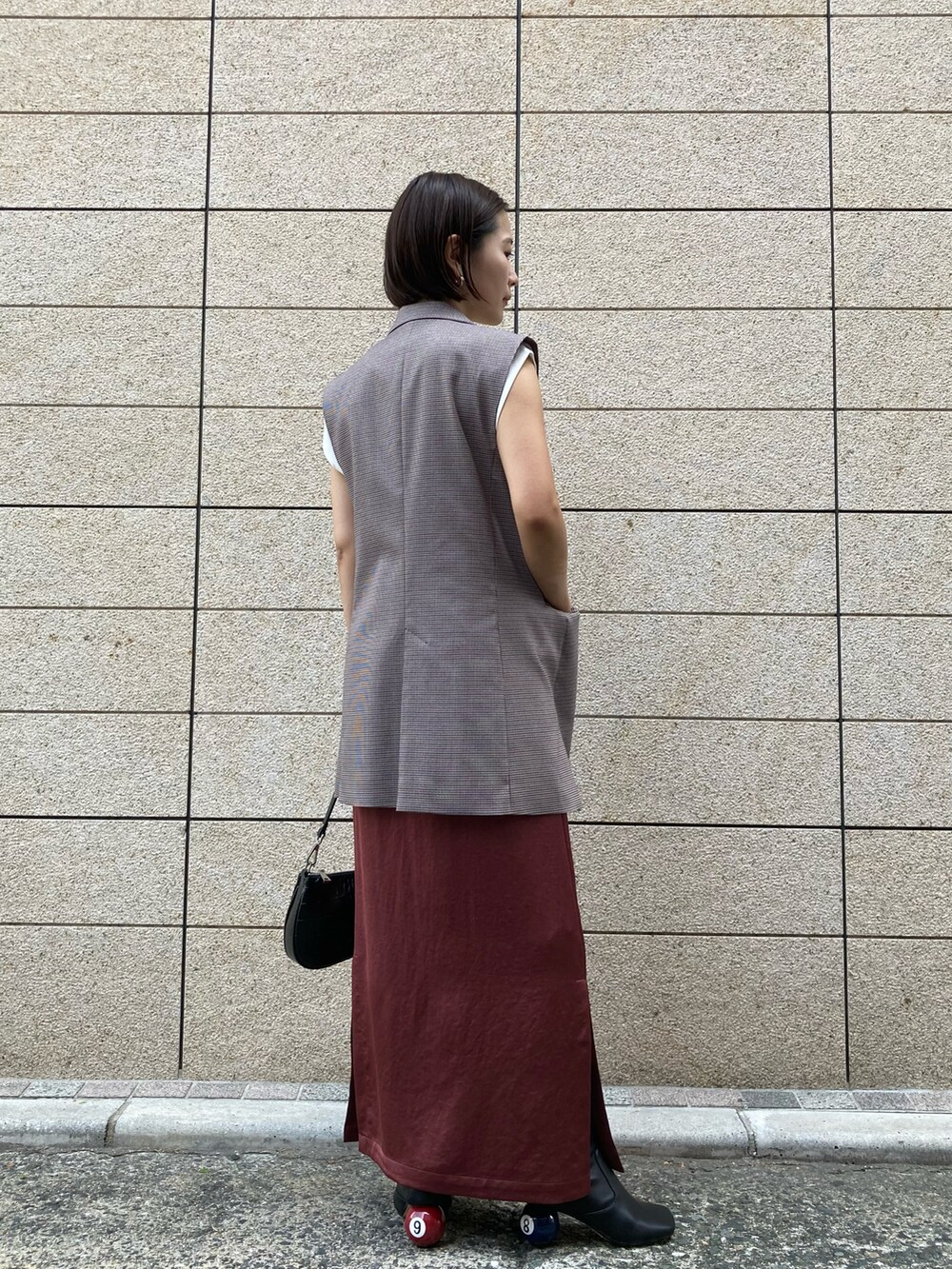 ブラック系のブーツ、ベージュ系のベスト、ホワイト系のTシャツ/カットソーを着用したレディースの秋コーディネートの2枚目の写真