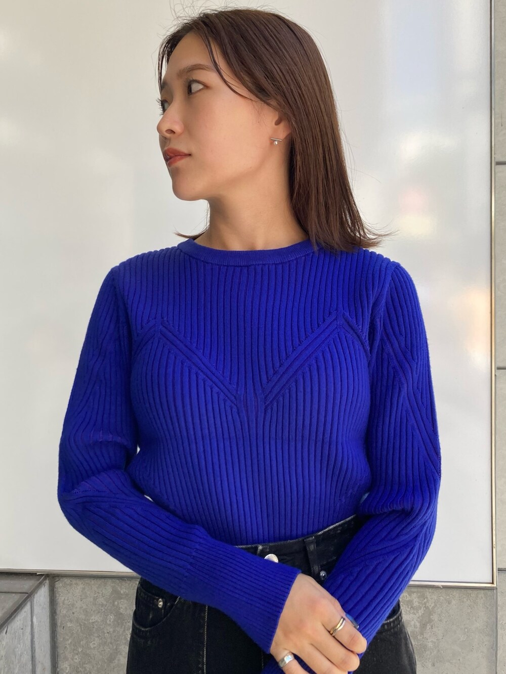 ブルー系のニット/セーター、ブラック系のデニムスカートを着用したレディースの秋コーディネートの4枚目の写真