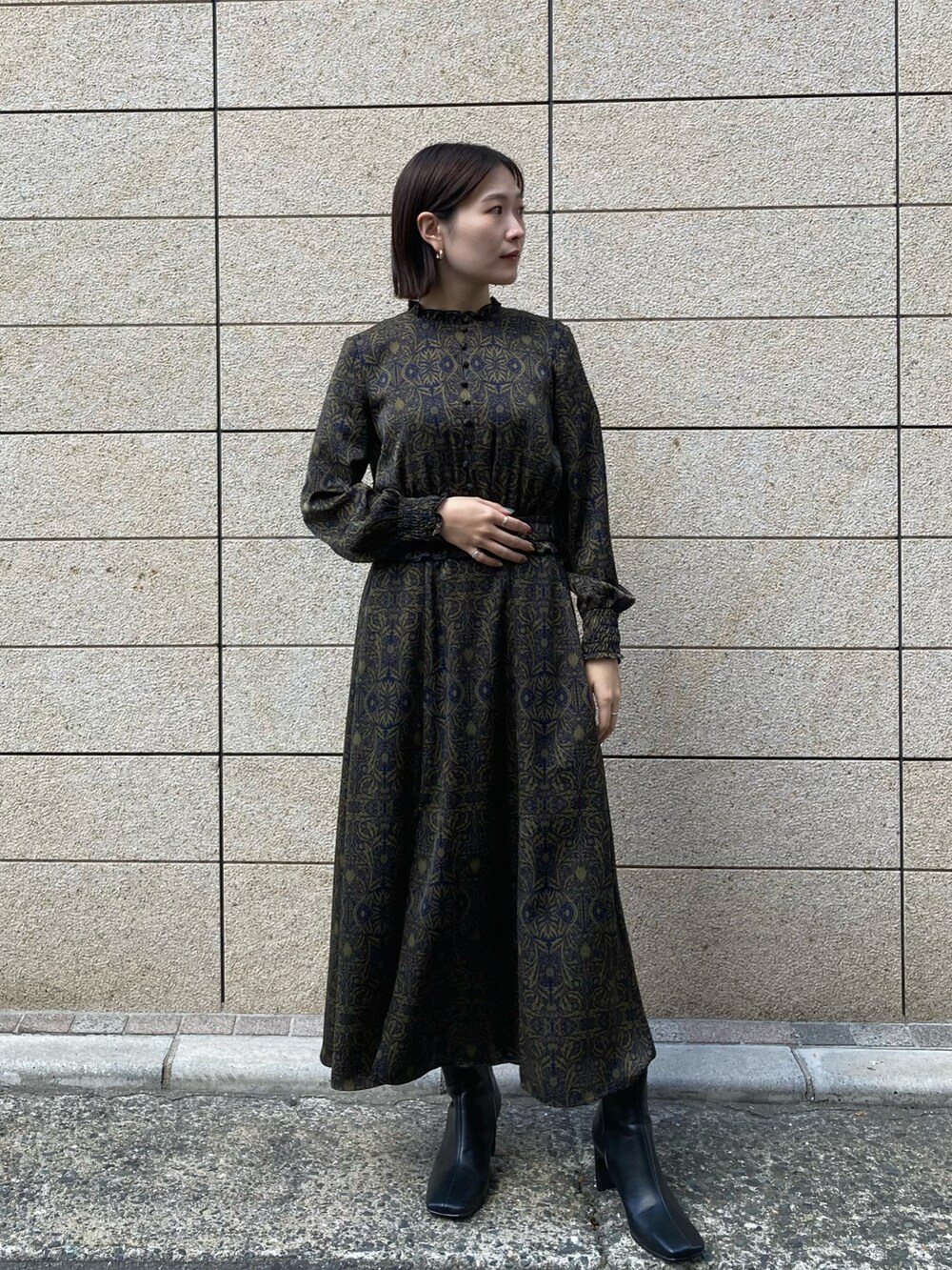 ホワイト系のブルゾン、ブルー系のワンピース、ブラック系のブーツを着用したレディースの秋コーディネートの3枚目の写真