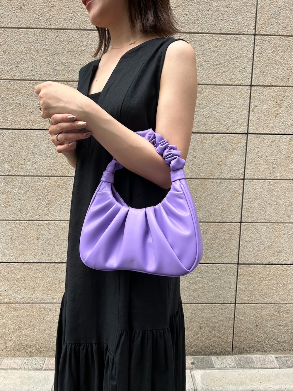 パープル系のハンドバッグ、ブラック系のスニーカー、ブラック系のワンピースを着用したレディースの夏コーディネートの3枚目の写真