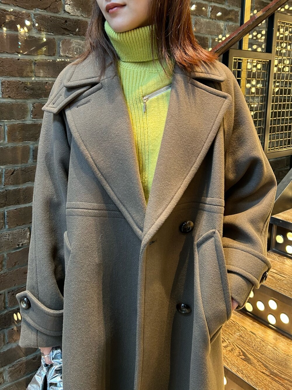 ブラウン系のチェスターコート、イエロー系のニット/セーター、ブラック系のその他パンツを着用したレディースの秋コーディネートの4枚目の写真