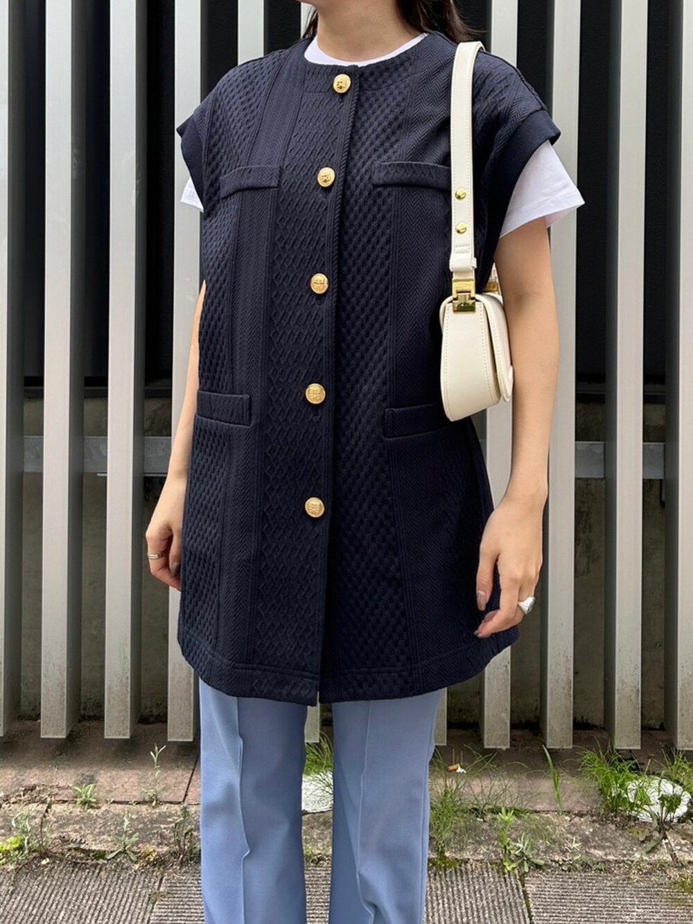 ホワイト系のハンドバッグ、ブルー系のベスト、ブルー系のその他パンツを着用したレディースの夏コーディネートの3枚目の写真