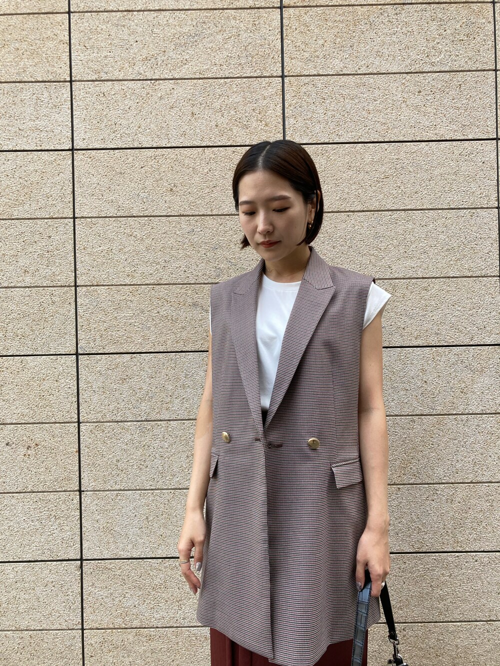 ブラック系のブーツ、ベージュ系のベスト、ホワイト系のTシャツ/カットソーを着用したレディースの秋コーディネートの3枚目の写真