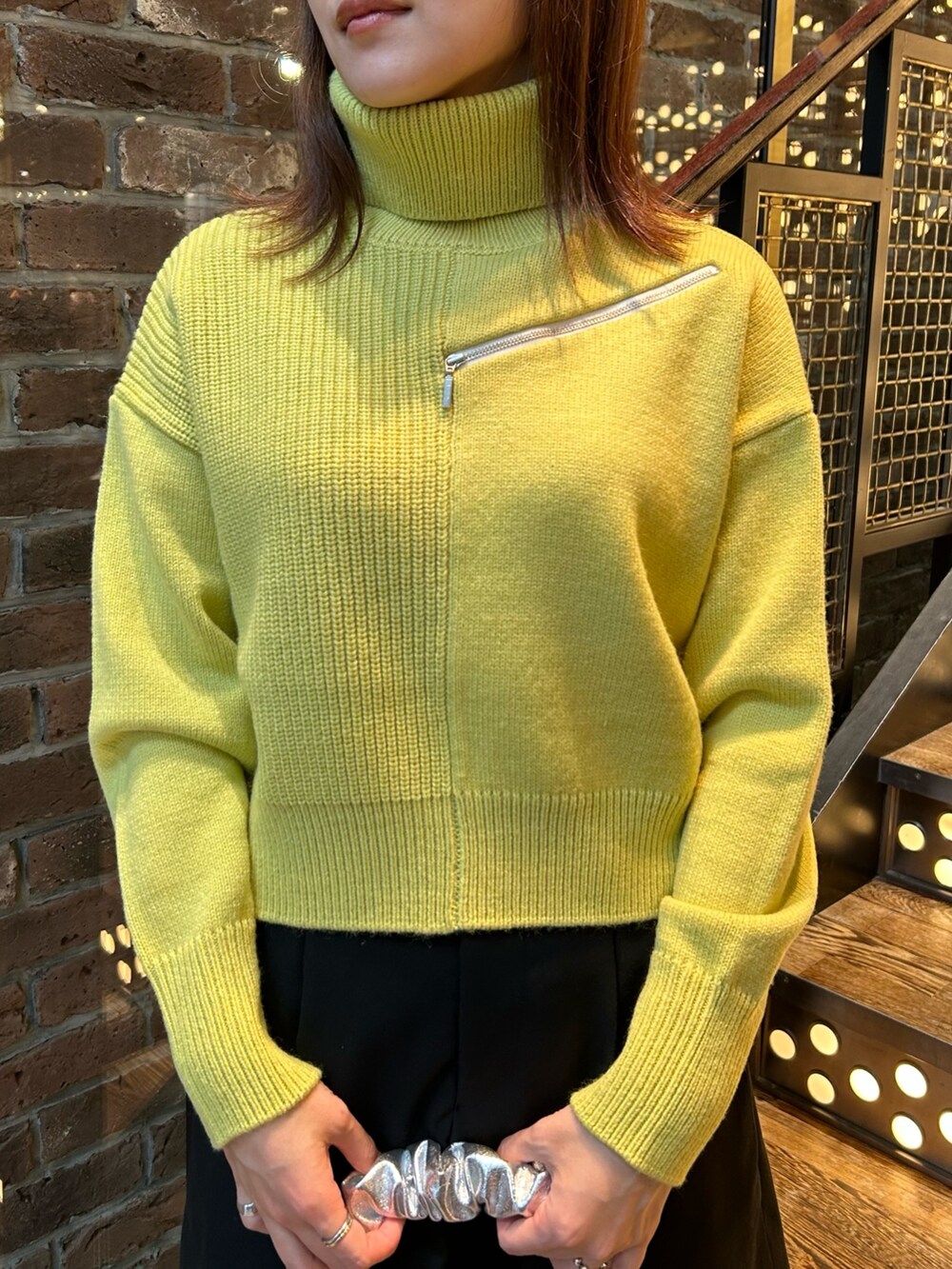 ブラウン系のチェスターコート、イエロー系のニット/セーター、ブラック系のその他パンツを着用したレディースの秋コーディネートの5枚目の写真